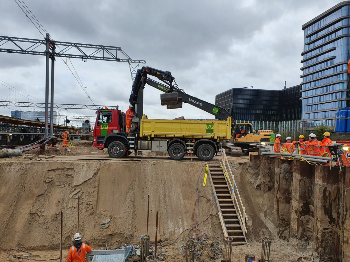 Kraanwagen laadt grond uit een diepe bouwput naast het spoor bij station Amsterdam Zuid