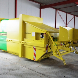 Perscontainer met hydraulische pers, opgesteld in een loods