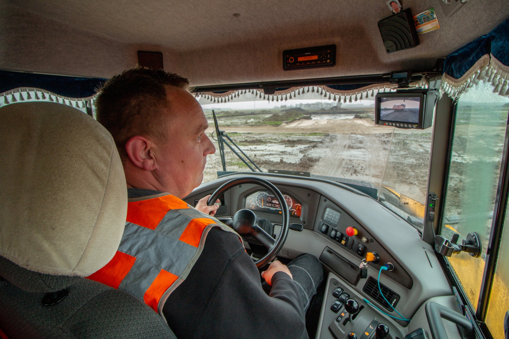 Machinist met veiligheidshesje aan het stuur in de cabine van een dumper